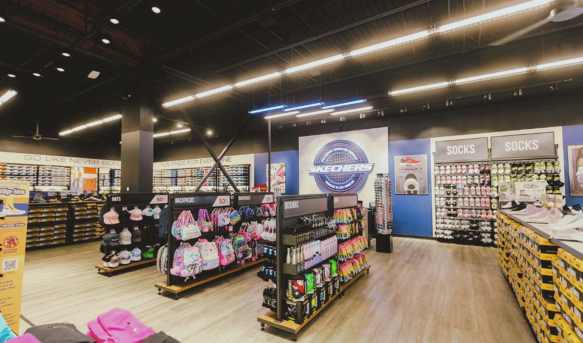 Skechers store interior with brick medallion logo wall and colorful accessory displays